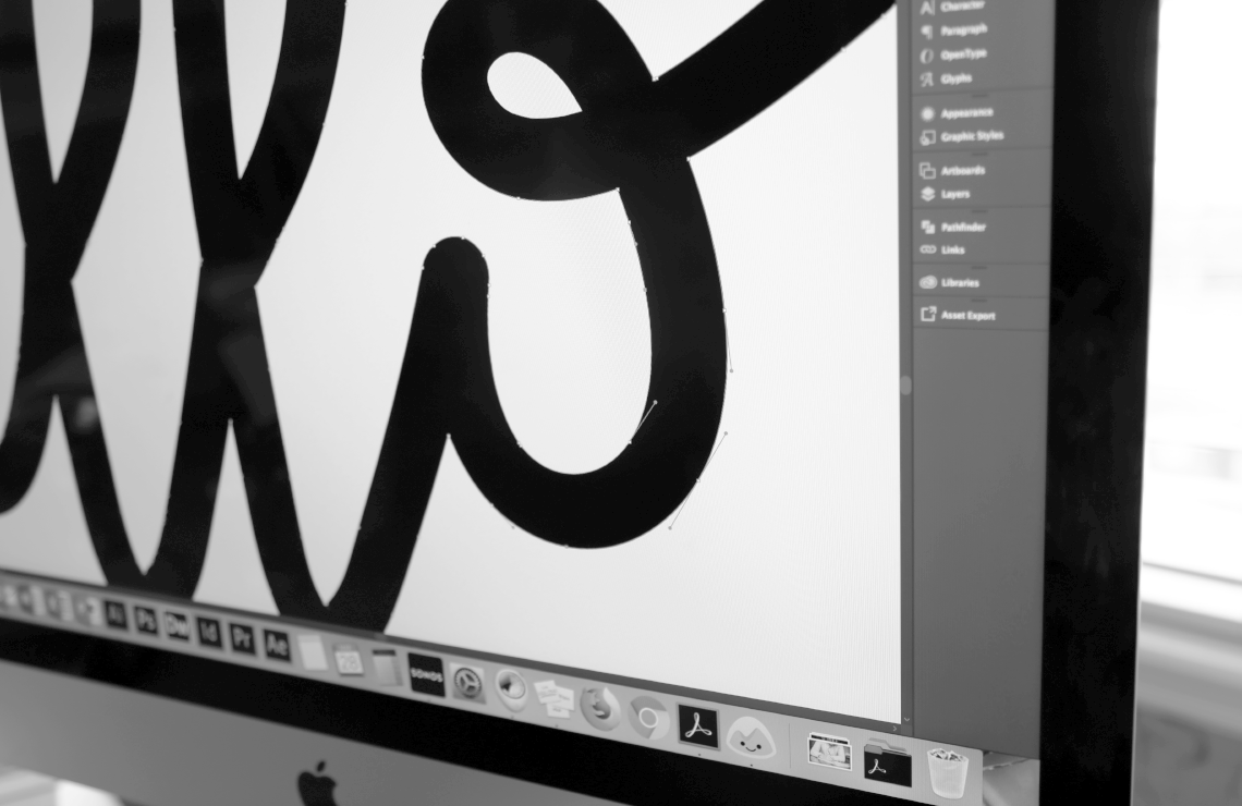 Close up image of a designer’s computer screen showing the detail of handwritten letterform paths in Adobe Illustrator.